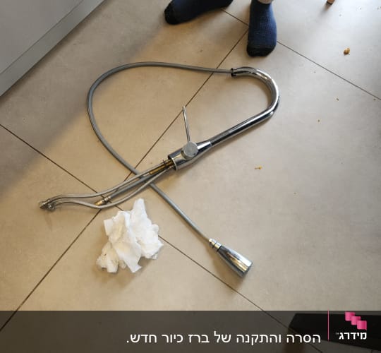 ברז מטבח מונח על הרצפה עם נייר טואלט